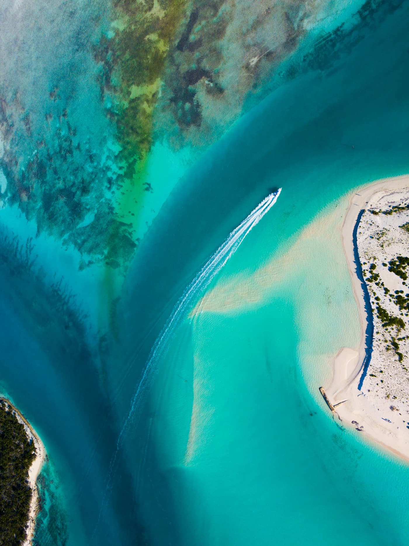 Looking straight down on a small boat crossing clear turquoise water
